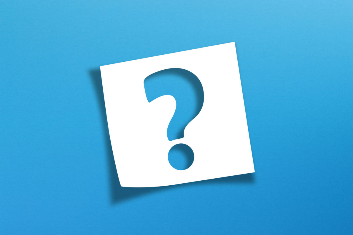 A blue question mark cut out on a white note paper over a blue background