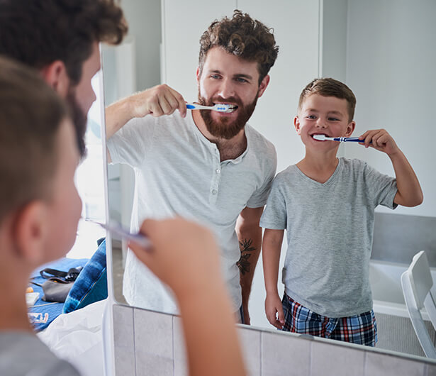 father and son brushing their teeth together